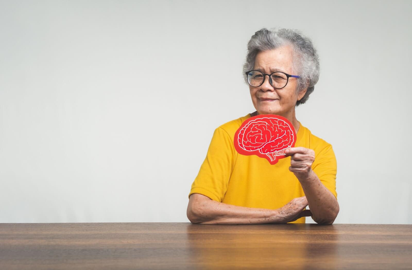An older adult holding a brain image to represent dementia.
