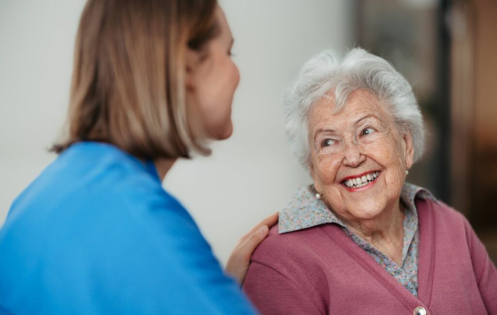 A caregiver supporting an older adult with dementia in memory care.